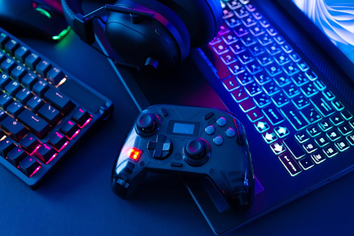 Top view of gaming gear including mouse, keyboard and controller on a black table