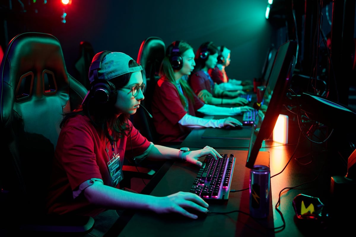 Group of players wearing headsets competing together at gaming computers